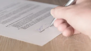 Pessoa assinando contrato de aluguel, destacando a importância de cláusulas essenciais no documento de locação.