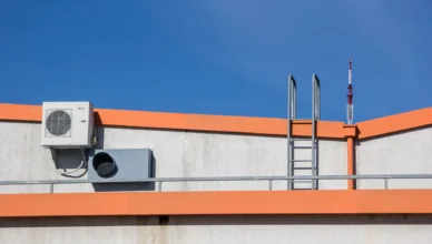Equipamentos de climatização industrial instalados no topo de um prédio em Curitiba, com unidade externa de ar-condicionado e dutos sobre estrutura metálica, ao céu azul.