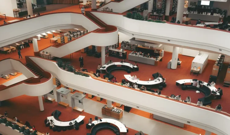 Interior de um museu ou centro cultural com corredores brancos em formato curvo, exposições e visitantes ao redor, em um ambiente amplo e iluminado. Vista geral do espaço, útil para ilustrar Intercâmbio no Canadá: Seu guia completo.